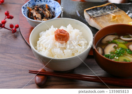 日式餐點,包括一份湯和三道小菜:米飯、味噌湯、一道小菜、一道小菜、烤鹹鯖魚、烤魚和梅子飯。 日式餐點,包括一份湯和三道小菜:米飯、味噌湯、一道小菜、一道小菜、烤鹹鯖魚、烤魚和梅子飯。 135985813