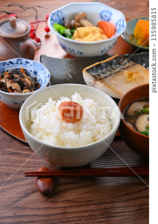日式餐點，包括一份湯和三道小菜：米飯、味噌湯、一道小菜、一道小菜、烤鹹鯖魚、烤魚和梅子飯。 135985815