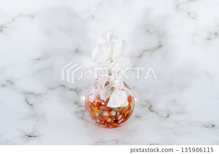 暖色調玻璃花瓶中的香豌豆（位於畫面中央） 135986115