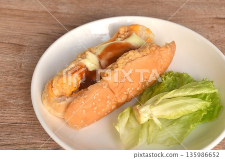 hot dog stuffed crispy fried chicken with lettuce dressing ketchup and mayonnaise on dish hot dog stuffed crispy fried chicken with lettuce dressing ketchup and mayonnaise on dish 135986652