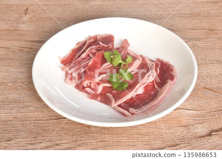 slice brisket beef raw food topping parslty arrangig in plate on table slice brisket beef raw food topping parslty arrangig in plate on table 135986653