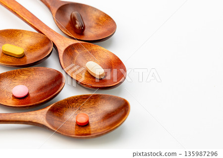 Single colorful vitamins and dietary supplements in wooden spoons on white background, natural herbal medicine and wellness concept Single colorful vitamins and dietary supplements in wooden spoons on white background, natural herbal medicine and wellness concept 135987296