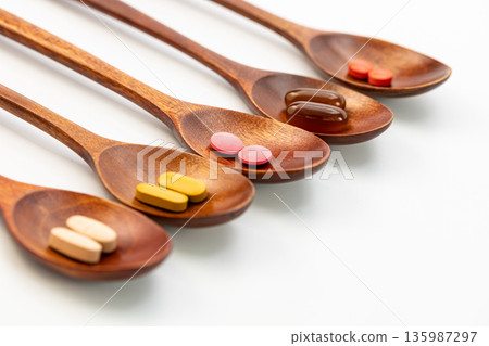 Various colorful vitamins and dietary supplements in wooden spoons on white background, natural herbal medicine and wellness concept Various colorful vitamins and dietary supplements in wooden spoons on white background, natural herbal medicine and wellness concept 135987297