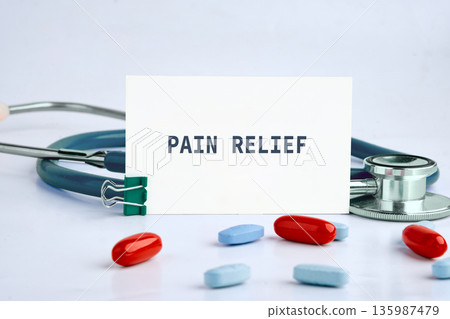 PAIN RELIEF card, stethoscope, red blue pills on a clean surface. Symbolizing healthcare, wellness, and recovery, ready to ease discomfort 135987479