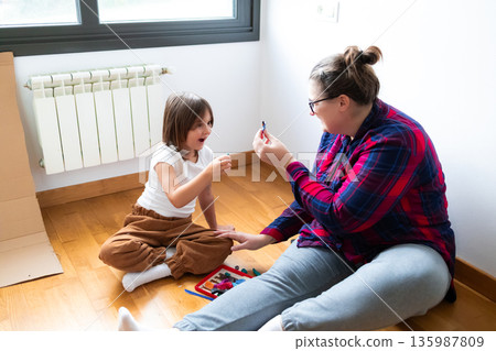 Caucasian female adult and child bonding over art in bright room 135987809