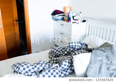 Cozy bedroom scene with unmade bed and wooden door Cozy bedroom scene with unmade bed and wooden door 135987820