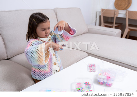 Young caucasian girl crafting with beads at home living room Young caucasian girl crafting with beads at home living room 135987824