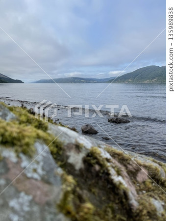 Loch ness water ripples along rocky shore in scotland 135989838