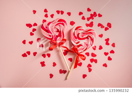 Valentine's Day festive background. Heart-shaped lollipops and heart confetti on pink background with copy space. Love concept Valentine's Day festive background. Heart-shaped lollipops and heart confetti on pink background with copy space. Love concept 135990232