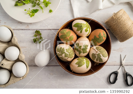 DIY Easter eggs with natural leaves, creating patterns on eggs using plants. Eco friendly colouring easter eggs 135990292