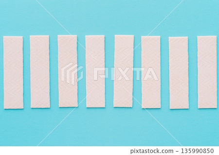 Chewing gum sticks aligned on turquoise background, minimal composition 135990850