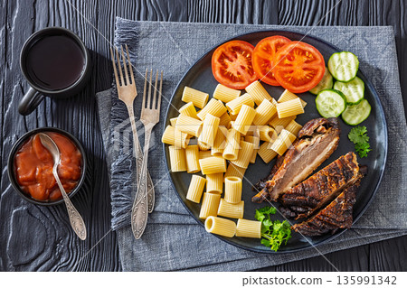 roasted pork ribs with pasta and fresh vegetables 135991342