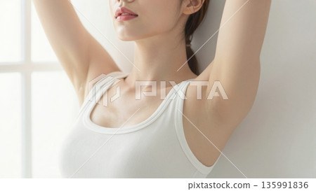 Minimal portrait of young woman stretching arms up in white tank top with soft natural light wellness concept 135991836