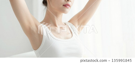Minimal portrait of young woman stretching arms up in white tank top with soft natural light wellness concept 135991845