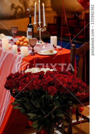 Romantic Red Rose Bouquet on a Candlelit Dinner Table with Wine and Balloons for Valentine's Day Celebration Romantic Red Rose Bouquet on a Candlelit Dinner Table with Wine and Balloons for Valentine's Day Celebration 135992362