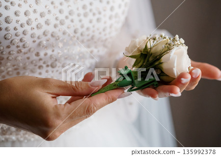 Elegant Bride Holding White Rose Bouquet with Pearl-Embellished Wedding Dress in Soft Natural Light Elegant Bride Holding White Rose Bouquet with Pearl-Embellished Wedding Dress in Soft Natural Light 135992378