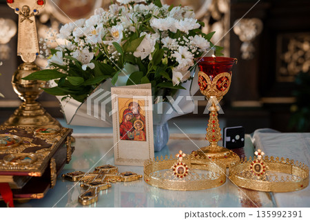 Ornate Religious Altar with Golden Chalice, White Flowers, and Icon of Holy Family in Church Interior 135992391