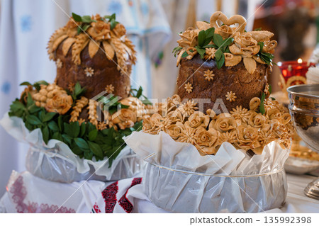 Ornate Traditional Easter Bread adorned with Decorative Dough Flowers and Green Leaves on a Festive Table Setting 135992398