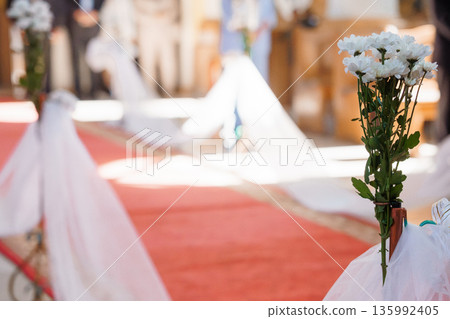 White Chrysanthemum Bouquet at Wedding Aisle with Red Carpet and Guests in Background White Chrysanthemum Bouquet at Wedding Aisle with Red Carpet and Guests in Background 135992405