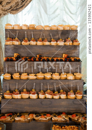 Rustic Wooden Tiered Display of Appetizers with Olives, Cheese, and Ham at Elegant Event Rustic Wooden Tiered Display of Appetizers with Olives, Cheese, and Ham at Elegant Event 135992421