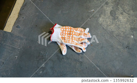 Construction gloves on an old stair landing in a multi-story building. Workwear and safety equipment for renovation or repair. Building maintenance. 135992632