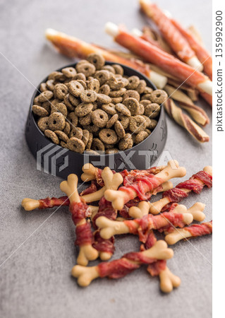 Dog food. Snack sticks for dogs and dry kibble food on gray table. 135992900