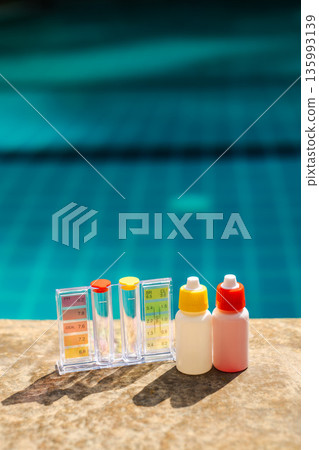 Pool water testing kit with pH and chlorine scale and reagent bottles on stone pool edge, swimming pool maintenance and water quality control concept with blue background Pool water testing kit with pH and chlorine scale and reagent bottles on stone pool edge, swimming pool maintenance and water quality control concept with blue background 135993139