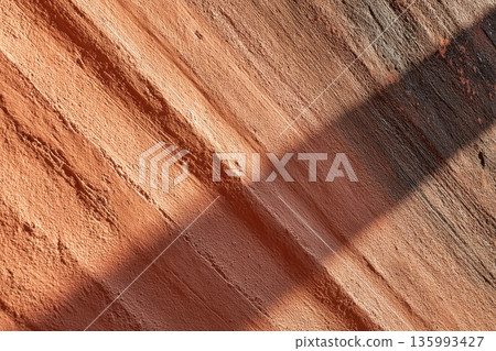 Textured Stucco Wall in Warm Coral Tones Captured in Summer Light with Dynamic Shadows 135993427