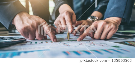 Confident Business People Analyzing Graphs on Table During Team Meeting and Discussion Confident Business People Analyzing Graphs on Table During Team Meeting and Discussion 135993503