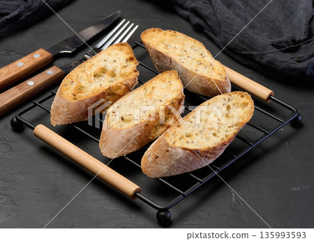 Slices of toasted grain baguette on the grill Slices of toasted grain baguette on the grill 135993593