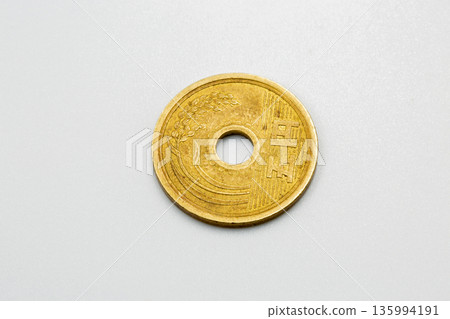 Japanese coin with hole on white background. 135994191