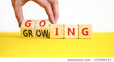 Going and growing symbol. Concept words Going Growing on beautiful wooden blocks. Beautiful white and yellow background. Businessman's hand. Business going and growing concept. Copy space. Going and growing symbol. Concept words Going Growing on beautiful wooden blocks. Beautiful white and yellow background. Businessman's hand. Business going and growing concept. Copy space. 135994325