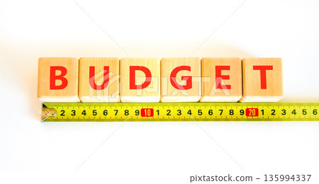 Budget symbol. Concept word Budget on beautiful wooden blocks. Beautiful white background. Beautiful yellow tape measure ruler. Business budget concept. Copy space. Budget symbol. Concept word Budget on beautiful wooden blocks. Beautiful white background. Beautiful yellow tape measure ruler. Business budget concept. Copy space. 135994337