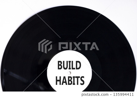 Build habits symbol. Concept word Build habits on beautiful black and white vinyl disk. Beautiful white paper background. Business build habits concept. Copy space. Build habits symbol. Concept word Build habits on beautiful black and white vinyl disk. Beautiful white paper background. Business build habits concept. Copy space. 135994411