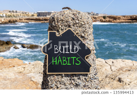 Build habits symbol. Concept word Build habits on beautiful black blackboard. Beautiful stone and blue sea sky background. Black blackboard. Business build habits concept. Copy space. Build habits symbol. Concept word Build habits on beautiful black blackboard. Beautiful stone and blue sea sky background. Black blackboard. Business build habits concept. Copy space. 135994413