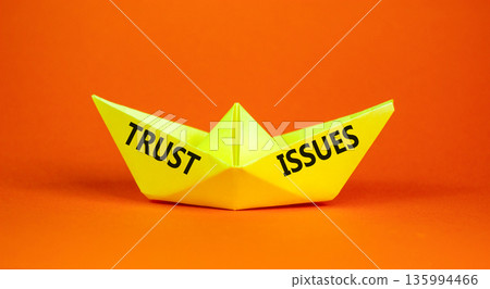 Trust issues symbol. Concept word Trust issues on beautiful yellow paper boat. Beautiful orange paper background. Business trust issues concept. Copy space. Trust issues symbol. Concept word Trust issues on beautiful yellow paper boat. Beautiful orange paper background. Business trust issues concept. Copy space. 135994466