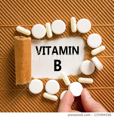Vitamin B symbol. Concept words Vitamin B on beautiful white paper. White pills tablets. Doctor's hand. Beautiful brown background. Medical healthy lifestyle Vitamin B concept. 135994506
