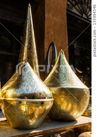Ornate brass table lamps displayed in a market. Various shapes and sizes, reflecting traditional Egyptian craftsmanship. Ideal for Ramadan decor. Ornate brass table lamps displayed in a market. Various shapes and sizes, reflecting traditional Egyptian craftsmanship. Ideal for Ramadan decor. 135994546