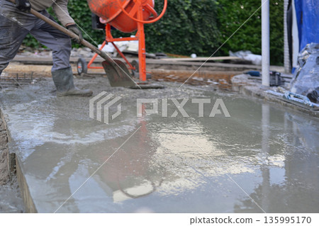 Worker Pouring and Spreading Fresh Concrete Slab in Formwor. Worker Pouring and Spreading Fresh Concrete Slab in Formwor. 135995170