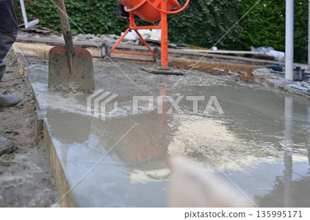 Worker Pouring and Spreading Fresh Concrete Slab in Formwor. Worker Pouring and Spreading Fresh Concrete Slab in Formwor. 135995171