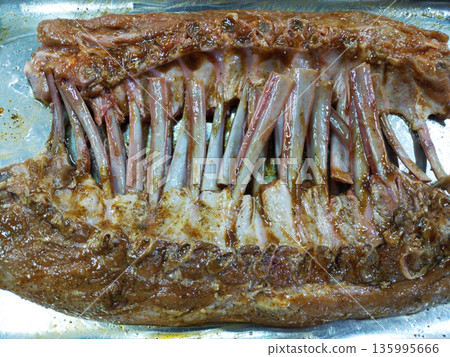 Marinated ribs are placed in a stainless steel dish and prepared for baking Marinated ribs are placed in a stainless steel dish and prepared for baking 135995666