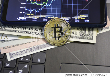 A gold Bitcoin coin on dollar bills and a keyboard A gold Bitcoin coin on dollar bills and a keyboard 135995676