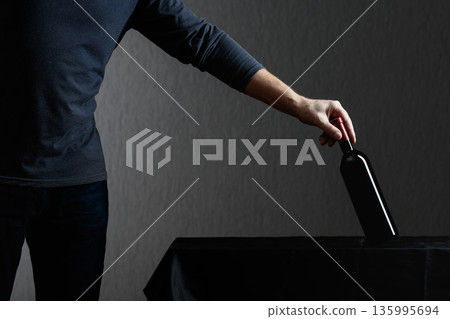 Man picks up a bottle of red wine. 135995694