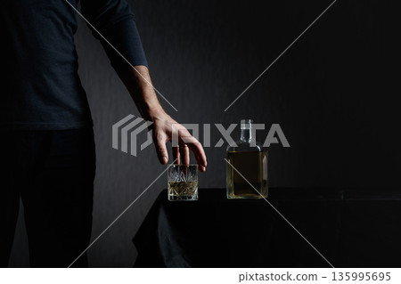 Man picks up a glass of strong alcoholic drink. 135995695