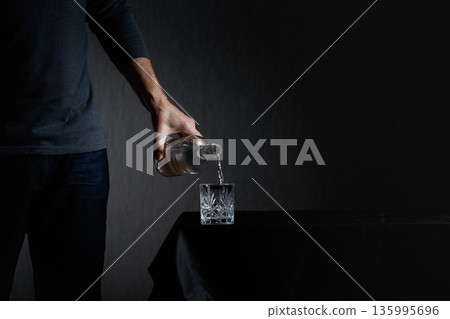 Man pouring strong alcoholic drink in glass. 135995696