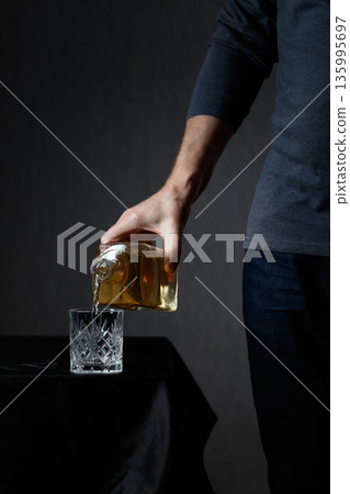 Man pouring strong alcoholic drink in glass. Man pouring strong alcoholic drink in glass. 135995697