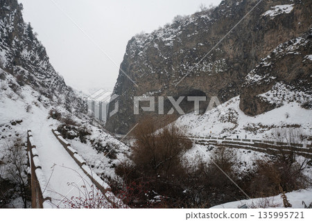Snow-covered cliffs, winding road frame dramatic basalt formations of Symphony of Stones, winter textures emphasize the rugged canyon landscape Snow-covered cliffs, winding road frame dramatic basalt formations of Symphony of Stones, winter textures emphasize the rugged canyon landscape 135995721