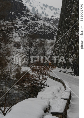 Snow-covered road and river run alongside towering basalt columns at the Symphony of Stones, dark volcanic textures contrast with winter whites Snow-covered road and river run alongside towering basalt columns at the Symphony of Stones, dark volcanic textures contrast with winter whites 135995729