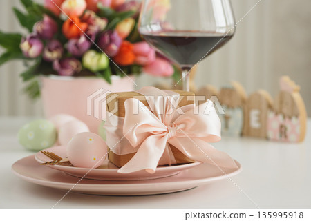 Easter Table Setting with Gift Box, Decorated Eggs, Wine Glass and Tulips. Festive Spring Lifestyle Easter Table Setting with Gift Box, Decorated Eggs, Wine Glass and Tulips. Festive Spring Lifestyle 135995918