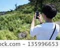 一名二十多歲的男子用智慧型手機拍攝初島的風景。 135996653